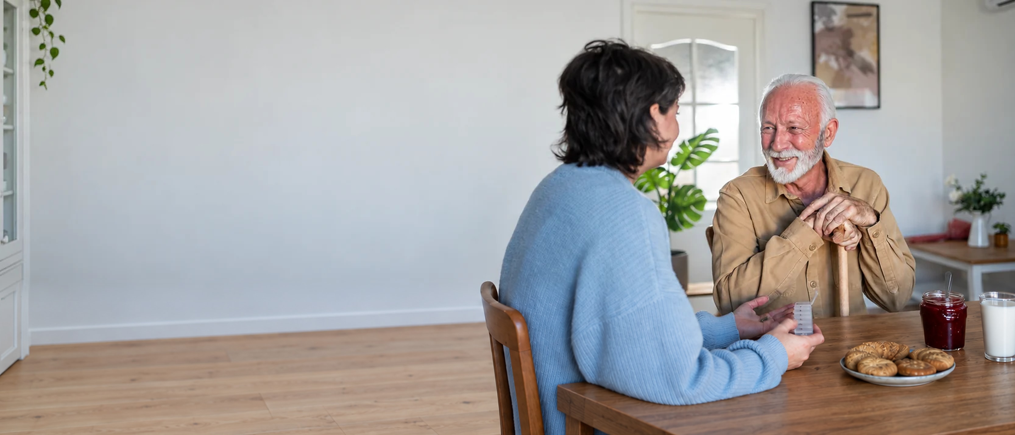 A Helper and a senior talking together at the kitchen table